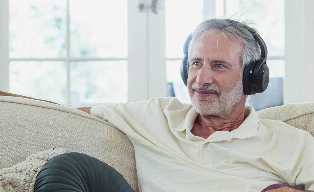 Persona mayor con auriculares viendo la tv